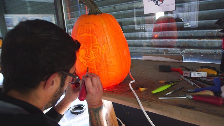 An artist at Maniac Pumpkin Carvers works on a pumpkin.