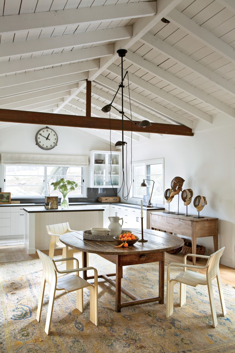 We reused our stacking chairs by Gijs Bakker around a nineteenth-century oval table in the kitchen of our main cabin. There’s an unusual nineteenth-century Swedish rug below. The chandelier is early twentieth-century by O. C. White. In the background, you can see the painted wood cabinetry and bluestone countertop as well as part of my collection of early American hand-carved bowls and stools, with vintage fencing masks from Europe.