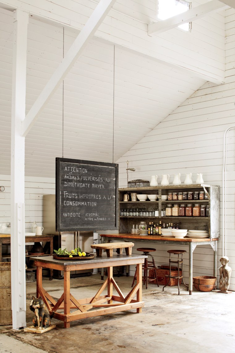 Here a vintage industrial kitchen rack with butcher-block top stores a selection of antique ironstone dishes and pitchers. The nineteenth-century bluestone table and a vintage American chalkboard made for the perfect prep area while entertaining.