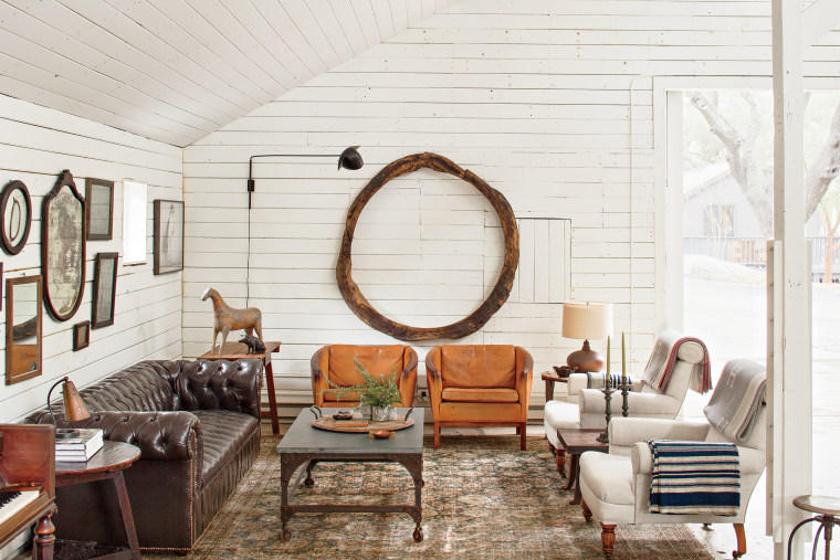 We used this barn like a dining room and kitchen. This seating area is made up of Danish leather armchairs, a bluestone coffee cocktail table, a pair of antique armchairs in Belgian linen, and a vintage leather chesterfield. On the floor is a nineteenth century tribal carpet, and on the wall hangs an eighteenth-century Spanish wood ring.