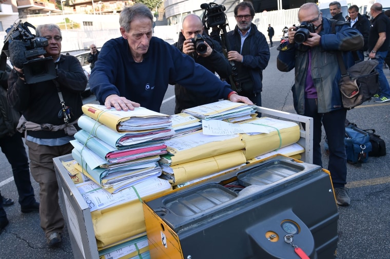 Image: An official pushes a cart with legal files into Rome's criminal court