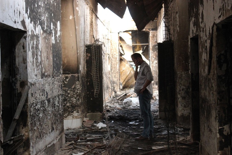 Image: An employee of Doctors Without Borders walks inside the charred remains of their hospital