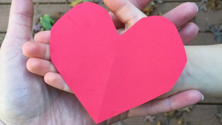 Two hands holding a paper heart