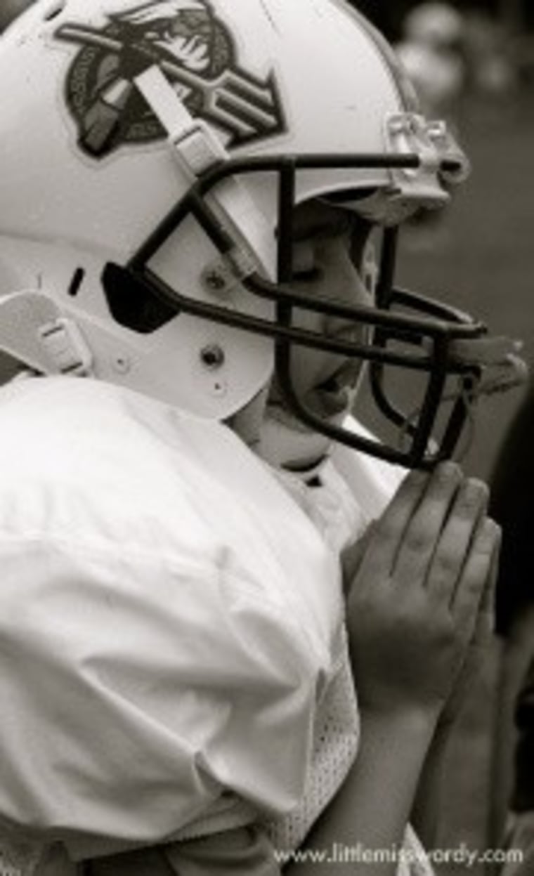 Boy praying in football uniform