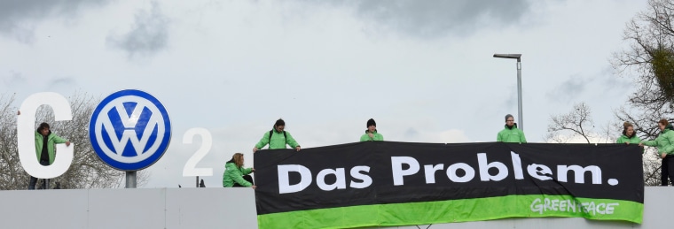 Image: Greenpeace activists demonstrate as they stand on top of Volkswagen's "Sandkamp" gate in Wolfsburg