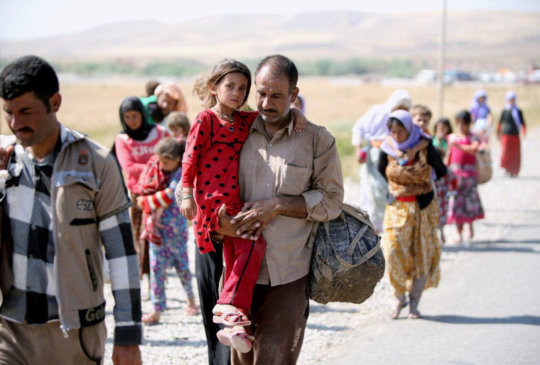 Image: A Yazidi man carries his daughter