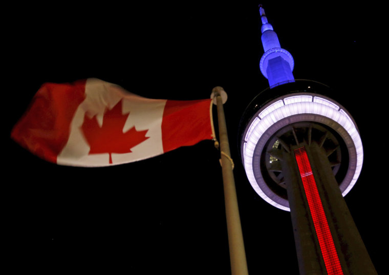 Image: Toronto's landmark CN Tower is lit blue, white and red in the colors of the French flag following Paris attacks