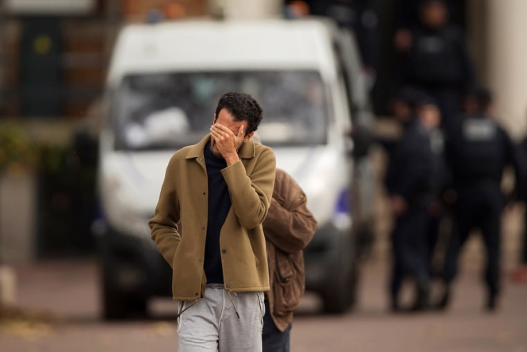 Image: A man hides his face as he leaves the morgue in Paris