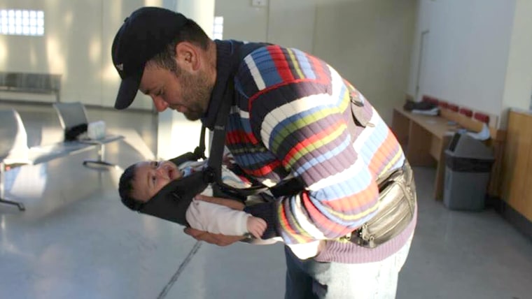 A father adjusts his one-month-old daughter in a donated baby carrier. His baby was born in Lebanon, and he said the family was fleeing Syria because it was no longer safe to raise. Even though baby-wearing is not prevalent in Syrian culture, many of the men like to be in charge of carrying the baby, as they have been leading the family through dangerous situations.