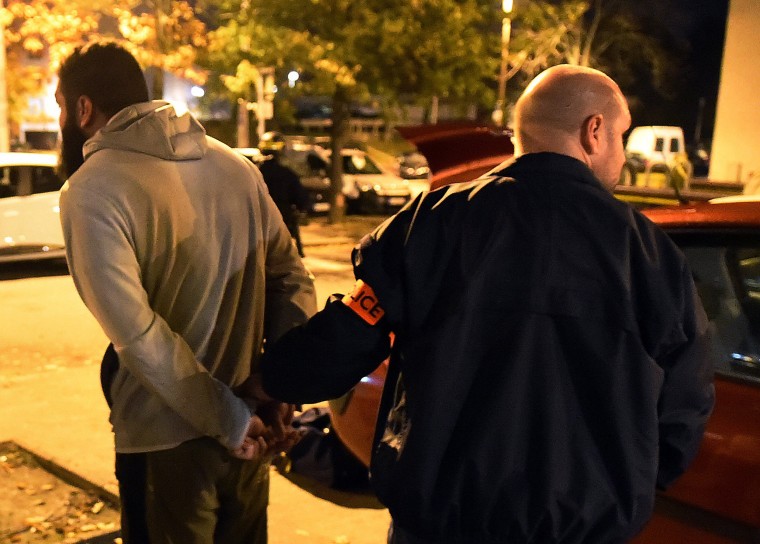 Image: A man is detained by a police officer after a raid in the Mirail district in Toulouse