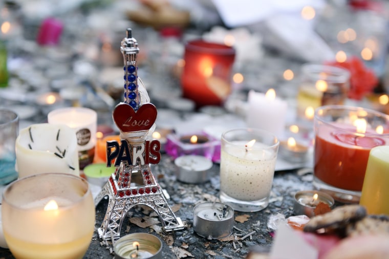 Image: Candles and a small statue of the Eiffel tower at a memorial