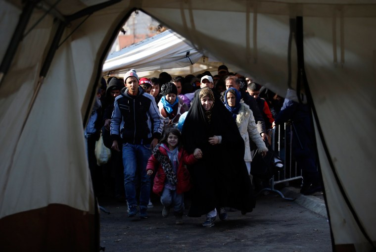 Image: Migrants walk into a tent to register with the police