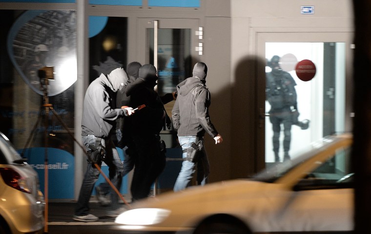Image: Policemen walk along a building