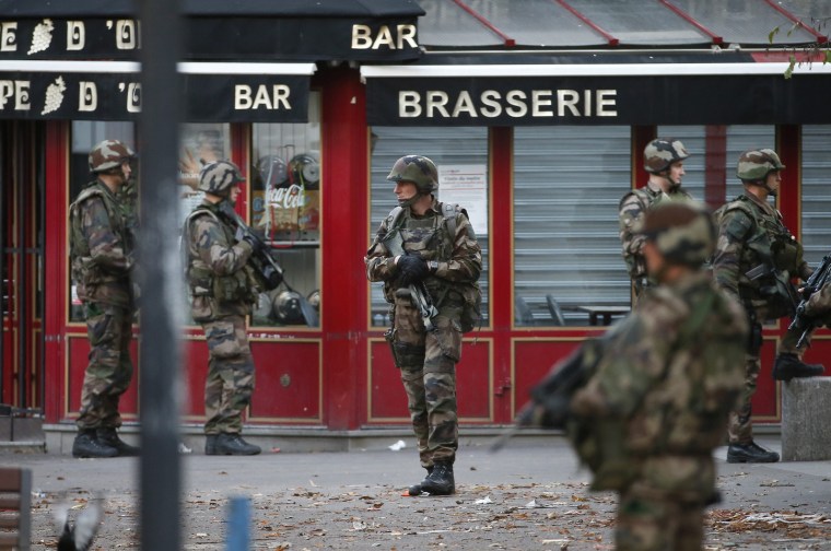 Image: French military members stand guard near the site of a raid