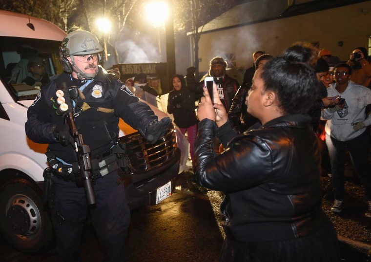 Image: A police officer tells a women to back up as she photographs him in front of a north Minneapolis police precinct in Minneapolis