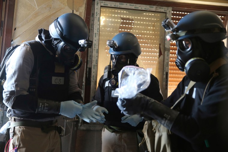 Image: A U.N. chemical weapons expert holds a plastic bag containing samples from one of the sites of an alleged chemical weapons attack in Ain Tarma