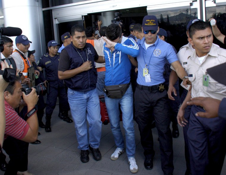 Image: Policemen escort one of five Syrian men detained at Toncontin international airport in Tegucigalpa