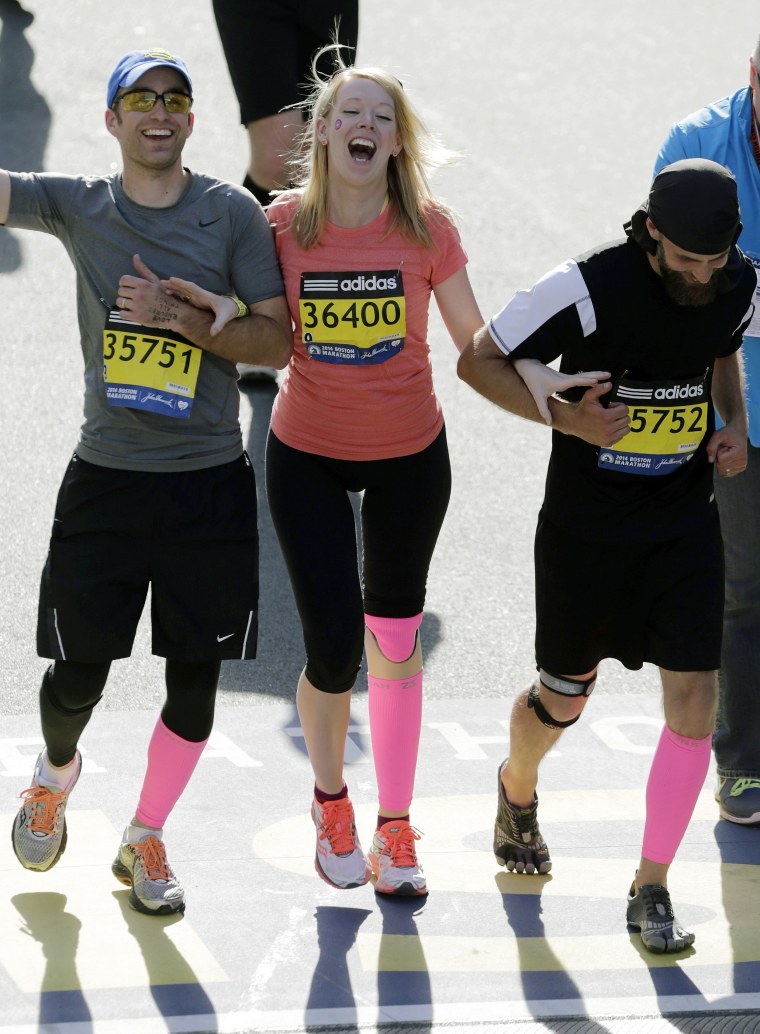 In this April 21, 2014 file photo, Timothy Haslet, left, and David Haslet, right, celebrate with their sister Adrianne Haslet-Davis as she crosses the finish line of the 118th Boston Marathon in Boston.