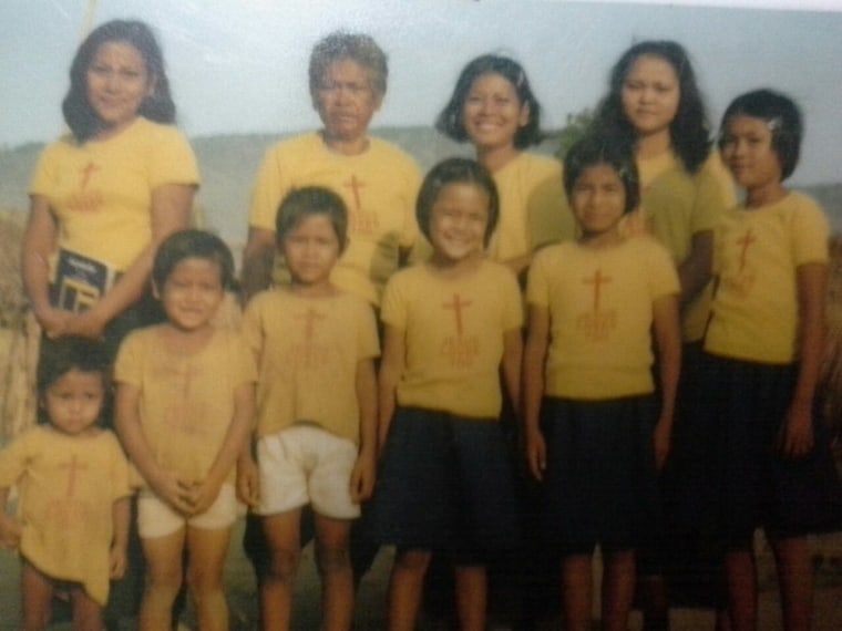 David Ros, second from the left, stands for a photo with his siblings, mother, and extended family. Ros and his family, who fled Cambodia together, are wearing T-shirts donated to them once they reached a refugee camp in Thailand.