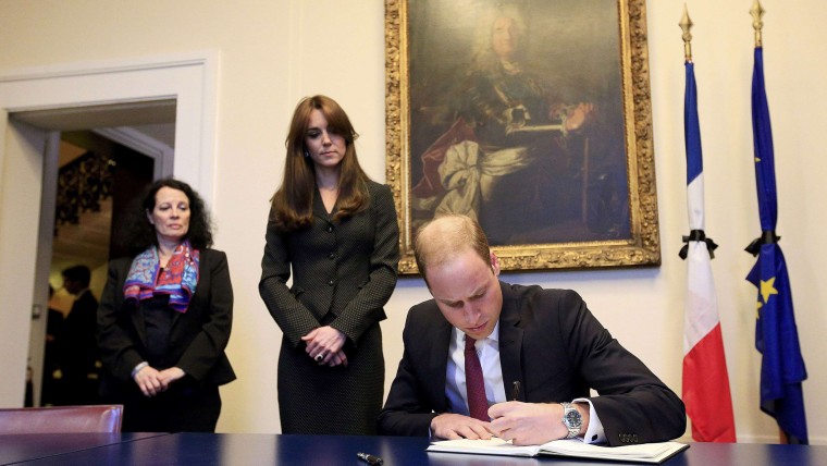 Image: Britain's Prince William, watched by Kate, the Duchess of Cambridge and French Ambassador to London Sylvie Bermann, signs the book of condolences for the victims of the attacks in Paris, at the French Embassy, Knightsbridge, London