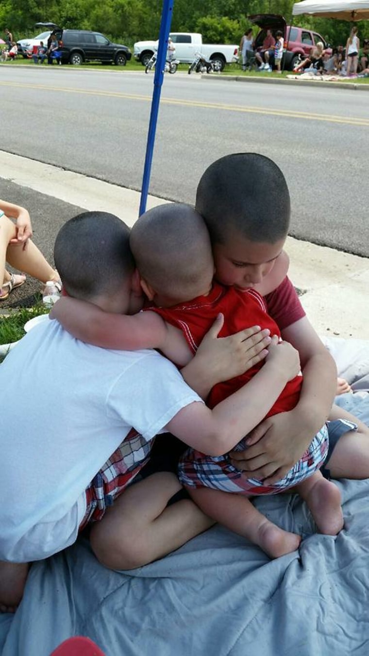 Big brothers hug and comfort their little brother after he tripped and fell.