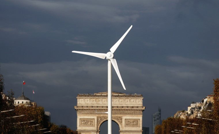 Image: A power-generating windmill turbine is seen in front of the Arc de Triomphe