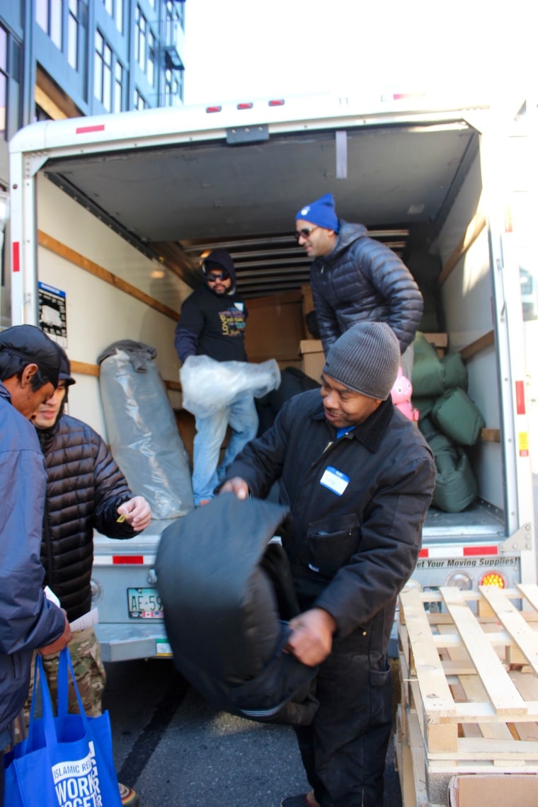 Volunteers unload a truck of special coats that also serve as sleeping bags.