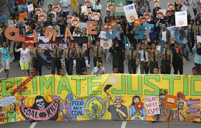 Image: People hold placards and banners as they participate in a march ahead of the Paris World Climate Change Conference in Jakarta