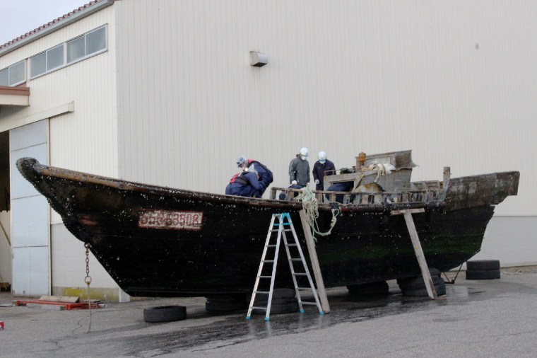 Image: Coast guard officials investigating a wooden boat