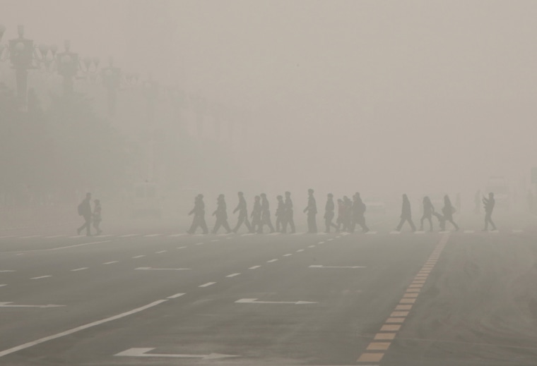 Image: Pedestrians and policeman cross the street at a crosswalk at the Tiananmen Square during a heavily polluted day in Beijing