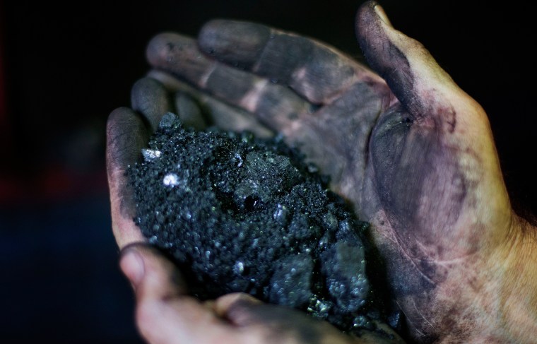 Image: Jackie Ratliff, a coal miner of 25 years, holds coal running through a processing plant