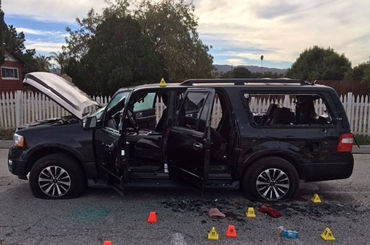 A bullet-riddled black SUV sits at the scene of a shootout between police and the couple who went on a rampage at the Inland Regional Center in San Bernardino, California.