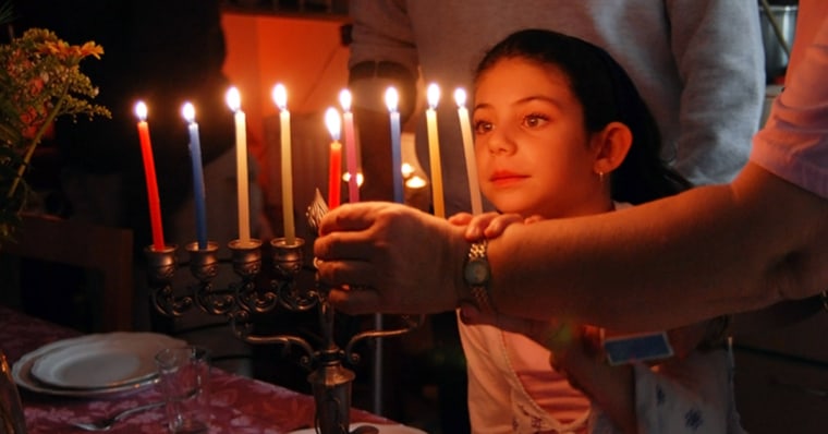 A family is lighting a candle for the Jewish holiday of Hanukkah.; Shutterstock ID 101422984; PO: today.com
