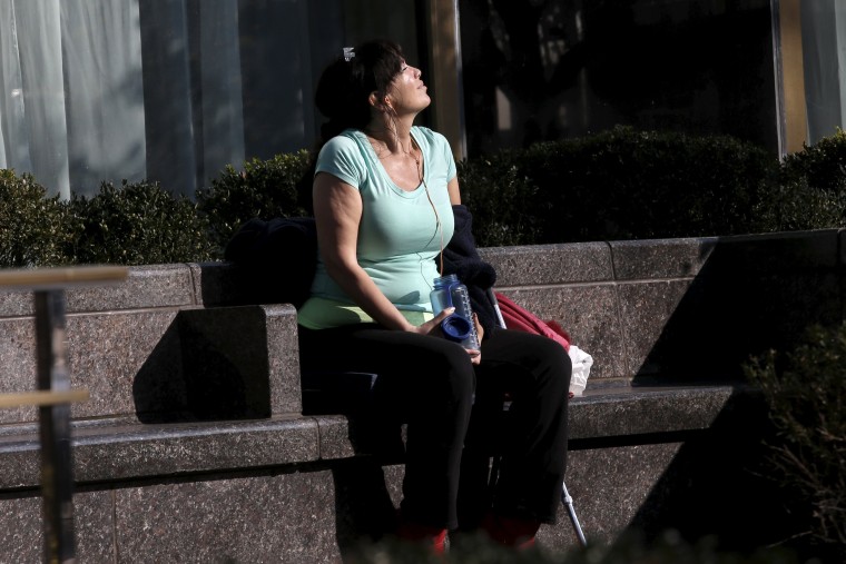 Image: A woman soaks up the sun as she sits outside in Midtown Manhattan in New York City
