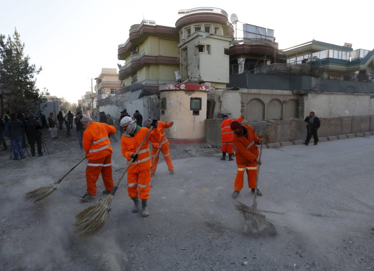 Image: Afghan municipality workers sweep a road after an attack on a guest house attached to the Spanish embassy in Kabul, Afghanistan