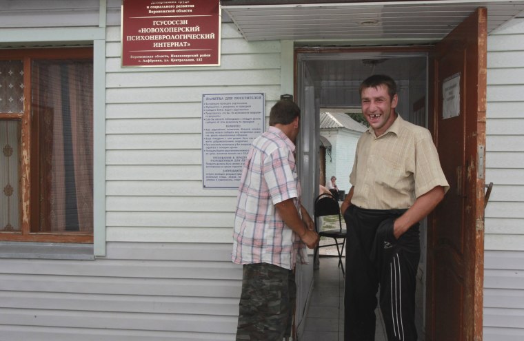 Image: Patients stand near a building of the Novokhopersky Neuropsychiatric Home in the village of Alferovka in the Voronezh region, Russia