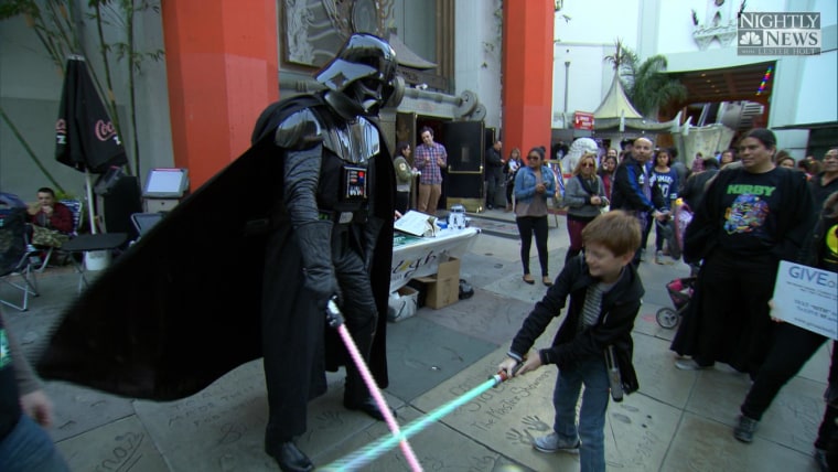 Fans waiting in line outside the TCL Theatre in Los Angeles engage in a friendly duel.