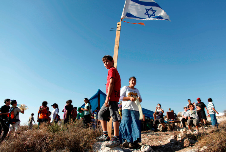 Image: Jewish settler youths gather on a hilltop near the West Bank settlement of Avnei Hefetz