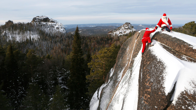 Image: Rescuers dressed as Santa Claus and Father Frost climb at Stolby National Nature Reserve during a training session of Russian Emergencies Ministry outside Krasnoyarsk