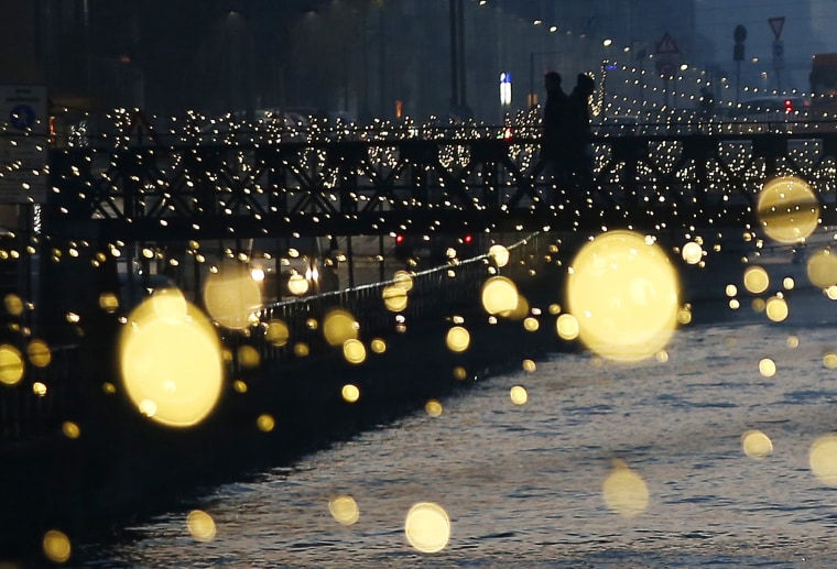 Image: People walk on a bridge as Christmas lights illuminate the Darsena dei Navigli