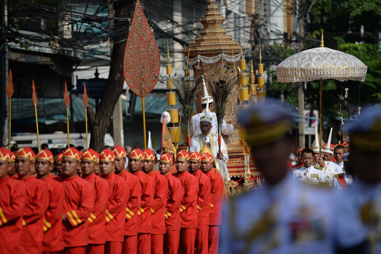 Image: Men in ceremonial uniforms use ropes to pull a carriage transporting the royal urn c