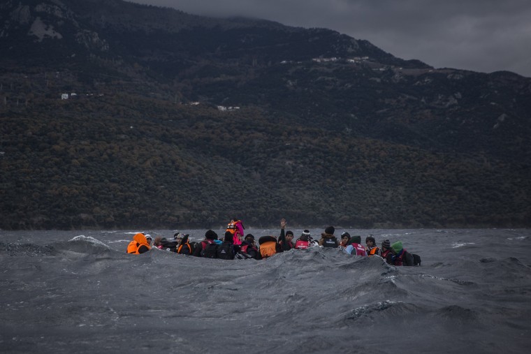Image: Refugees and migrants on a dinghy approach the Greek island of Lesbos