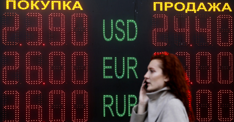 Image: Woman walks past board showing currency exchange rates in central Kiev