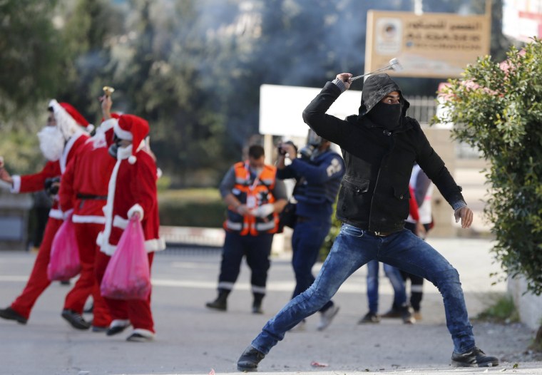 Image: Palestinian protester uses a sling to hurl stones towards Israeli troops during clashes following an anti-Israel protest in the West Bank city of Bethlehem