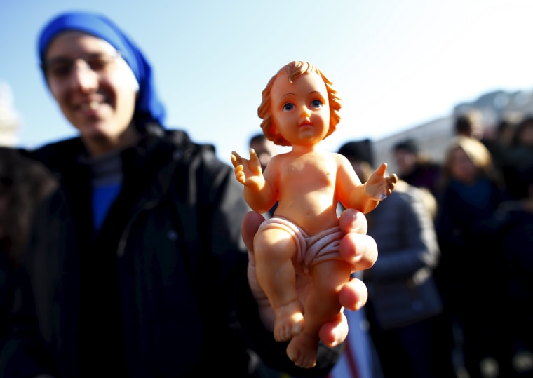Image: A nun holds a statue of baby Jesus as Pope Francis leads his Sunday Angelus prayer in Saint Peter's square at the Vatican