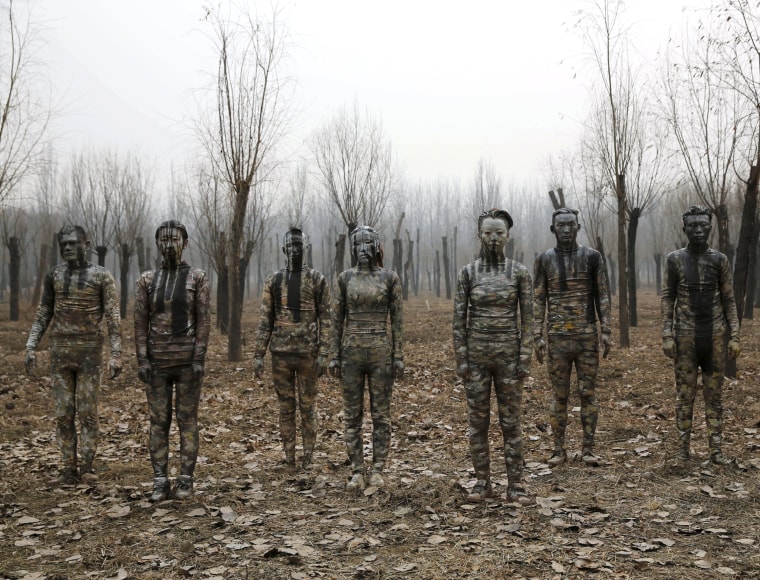 Image: Models painted in camouflage colours to blend in with the background pose for Chinese artist Liu Bolin's artwork \"Dongji\"