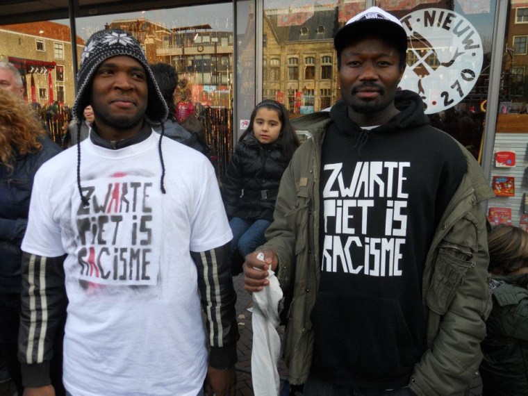 Quinsy Gario (left) and Jerry Afriyie (right) in silent protest at a 2011 Sinterklaas parade in the city of Dordrecht. Their violent arrests during the festivities for wearing t-shirts that read ‘Black Pete is Racist’ the resistance to Black Pete to the mainstream