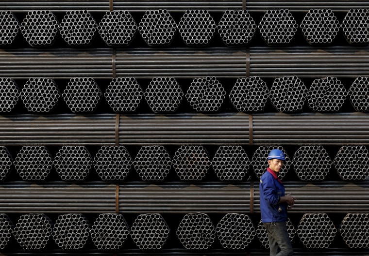 Image: File photo of a worker walking past a pile of steel pipe products at the yard of Youfa steel pipe plant in Tangshan in China's Hebei Province