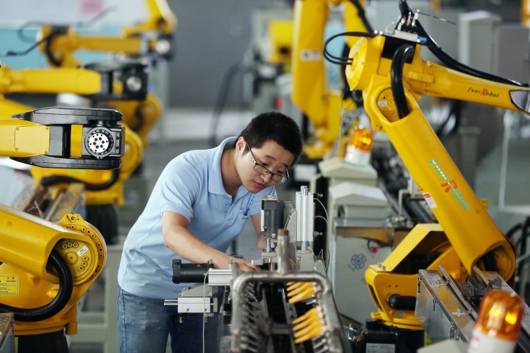 Image: Factory worker tests robot arms at factory in Jiaxing, China