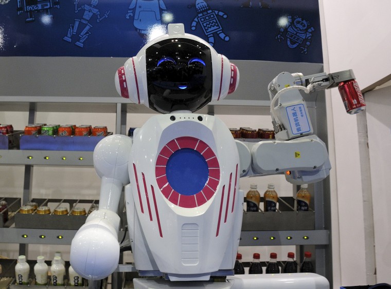 Image: A sales assistant robot picks up a can of Coca-Cola during a demonstration at the World Robot Conference in Beijing